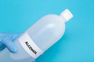 hands with protective glove holding a bottle of me XBWVT6Q scaled 1